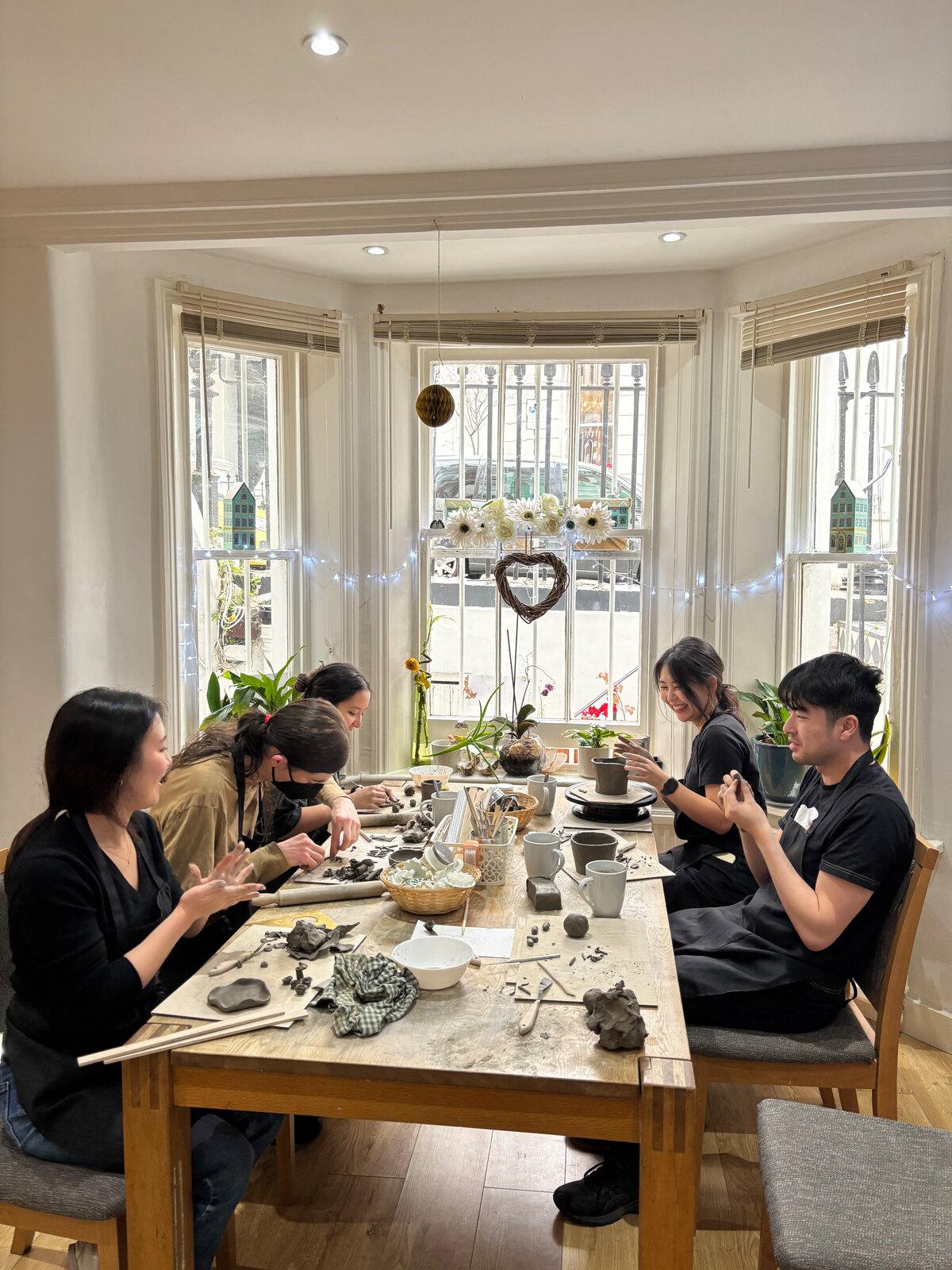 The team making pottery at a long table by the bay windows