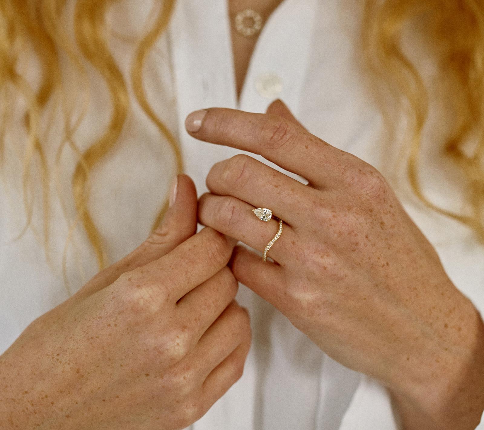 Gold ring with a pear-cut diamond worn on a hand