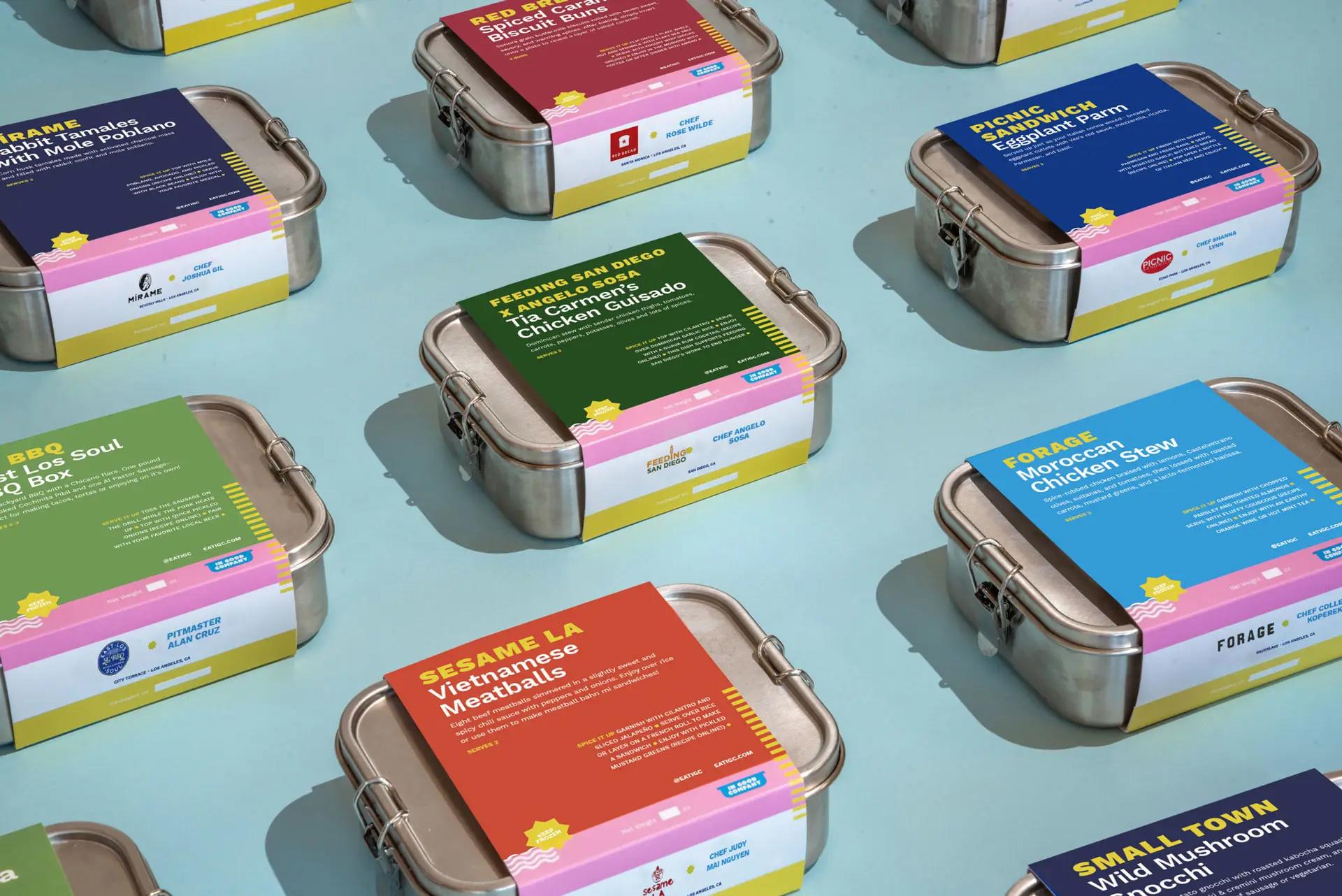 In Good Company meal boxes in reusable steel tins, laid out in rows with brightly colored recipe labels