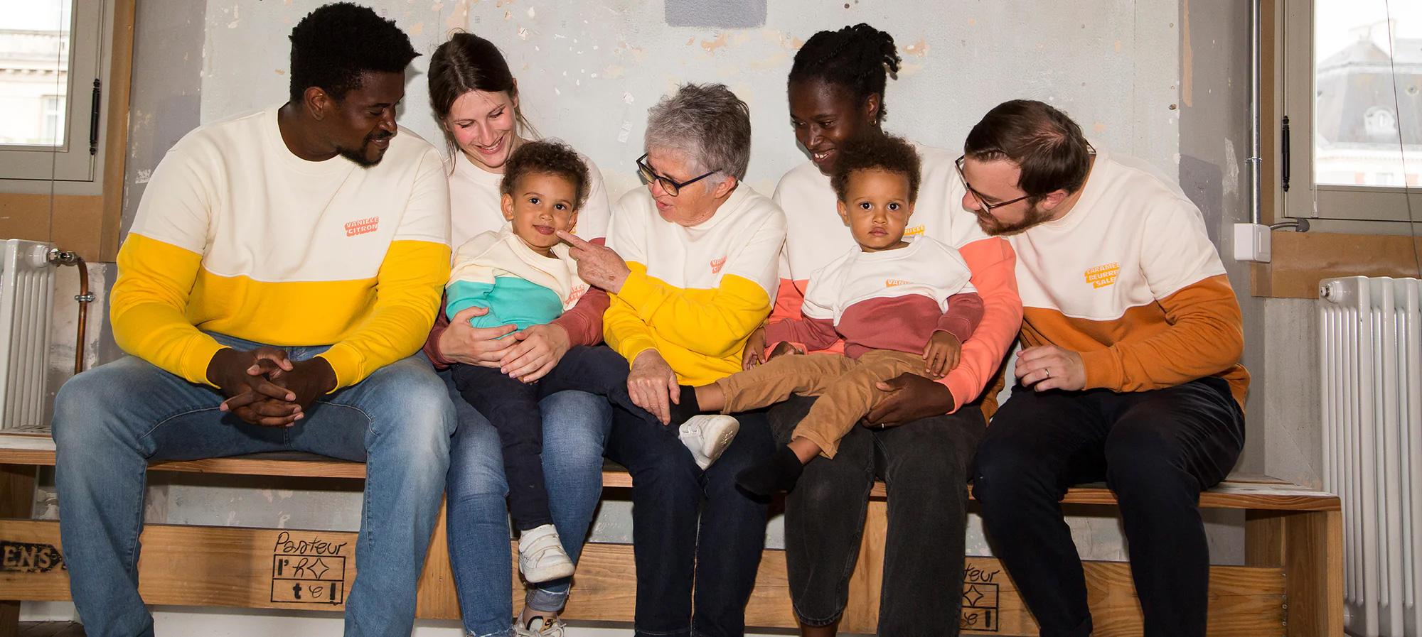 Adults and children wearing colorful Perpète clothing while sitting together