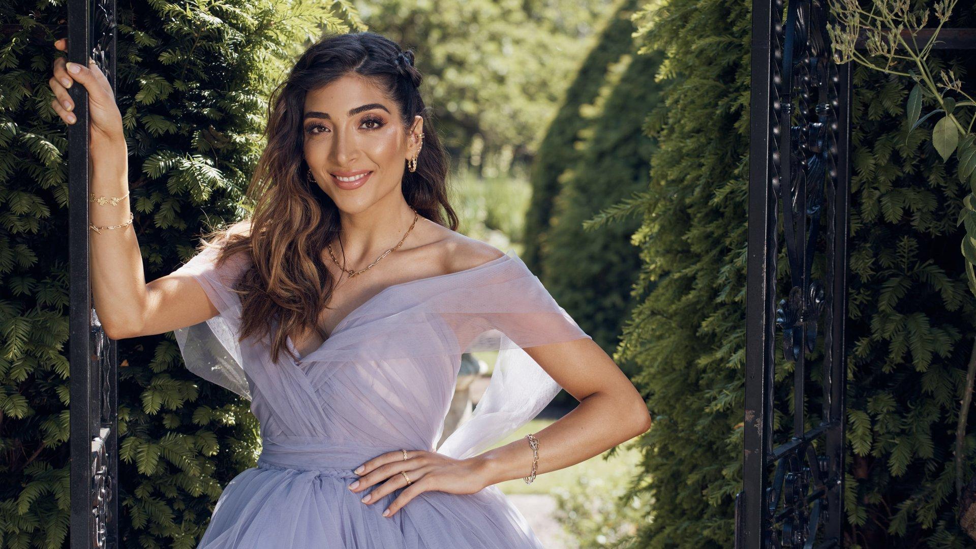 Woman in a lilac dress standing at the entrance to a garden