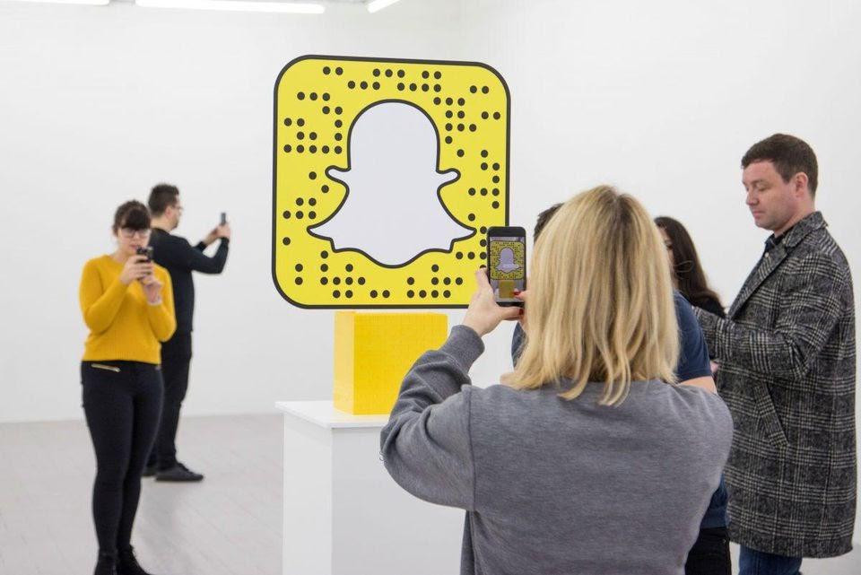 Visitors scanning a giant Snapchat Snapcode with their phones to open Lego's AR experience
