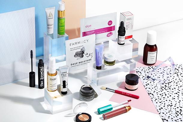 An assortment of beauty products from several brands arranged on white display blocks