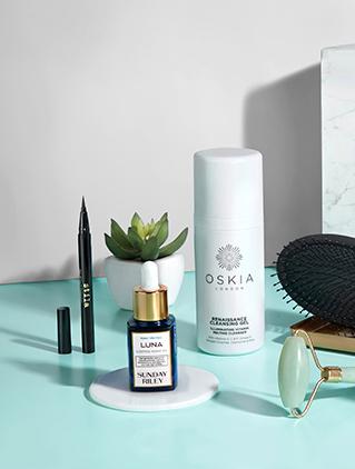 Skincare products and an eyeliner arranged with a succulent plant on a teal surface