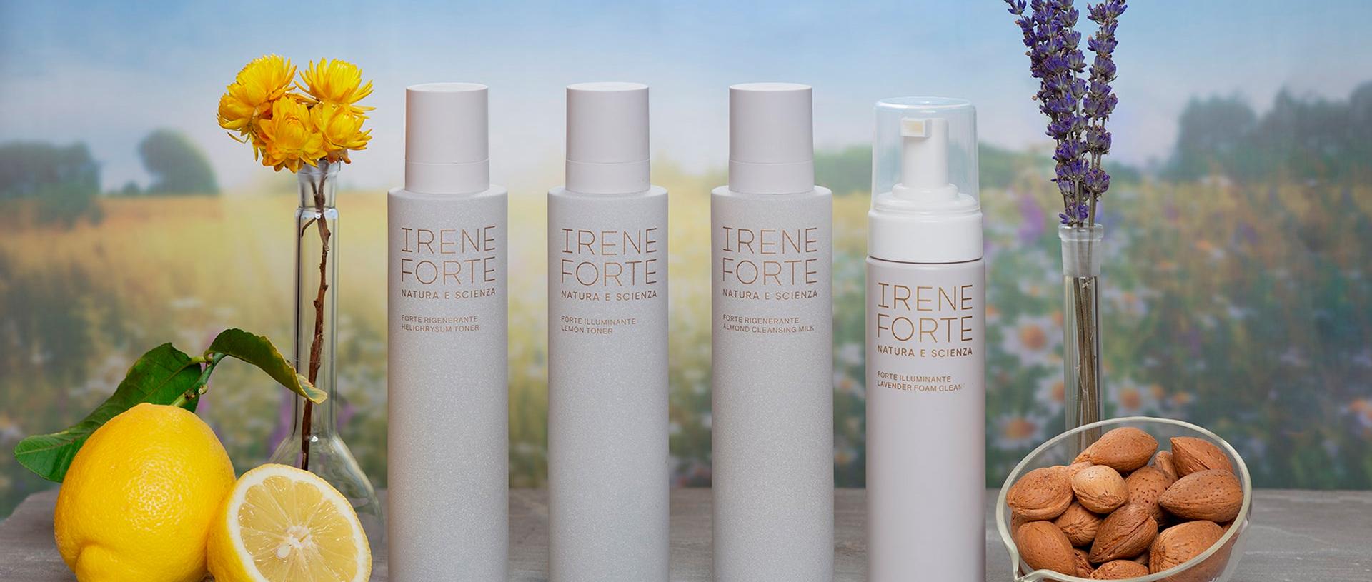 A row of Irene Forte skincare bottles styled with lemons, almonds and flowers