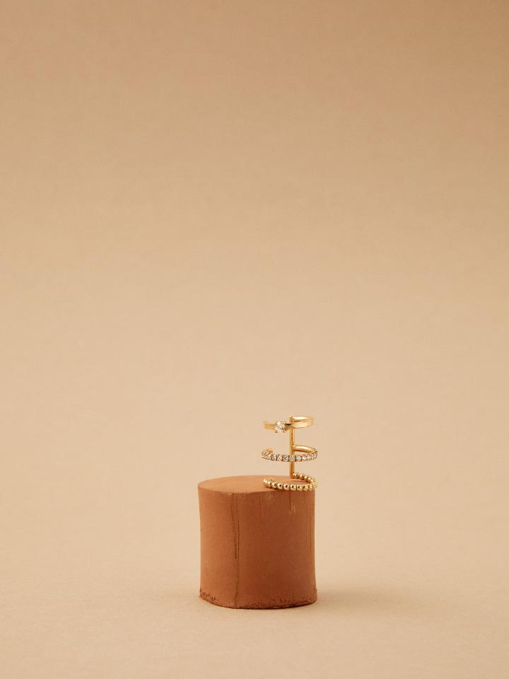 A Kimai gold ear cuff set with diamonds, displayed on a terracotta block