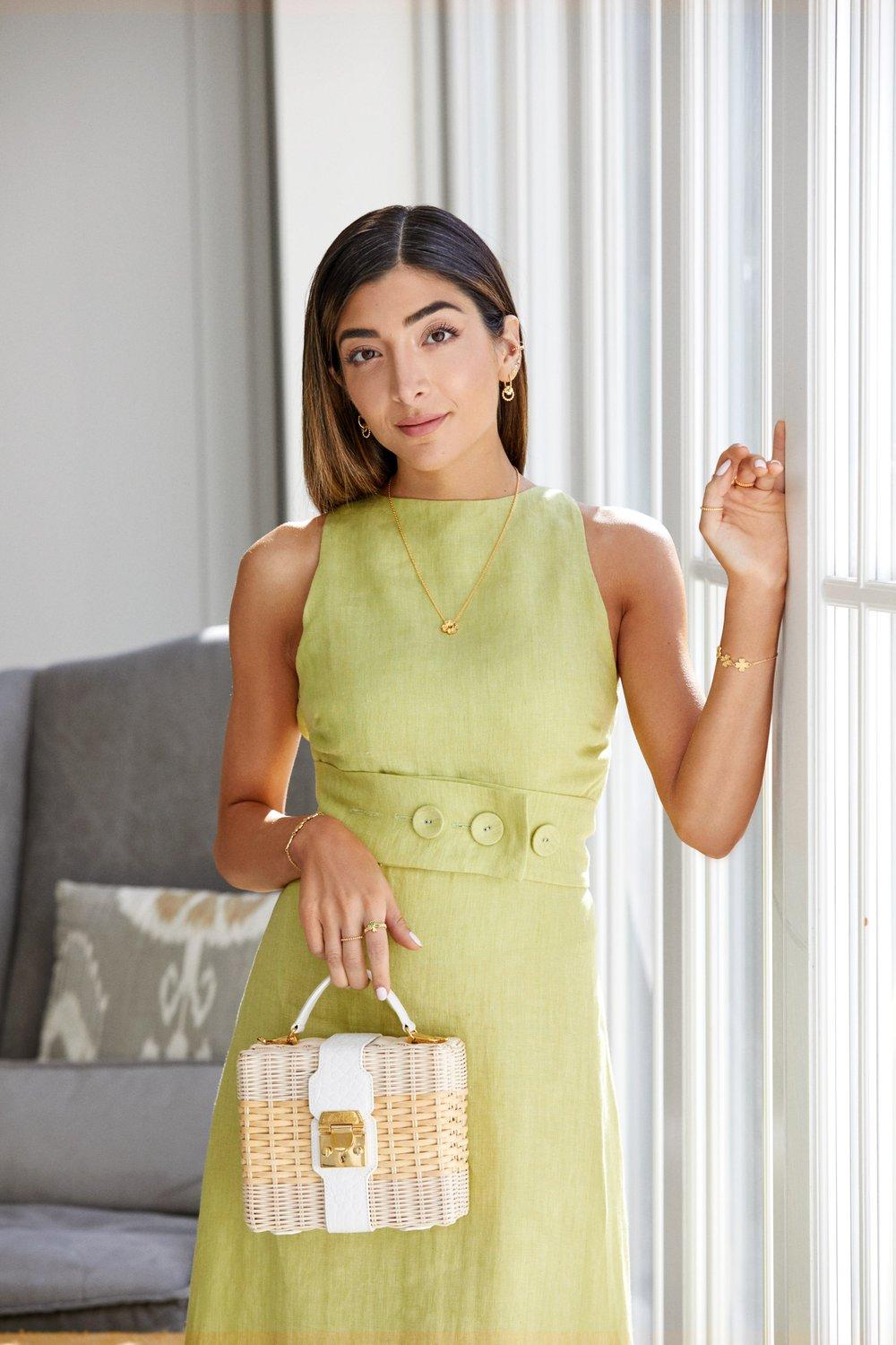 A model wearing Raemi gold jewelry: a pendant necklace, earrings, bracelet and rings